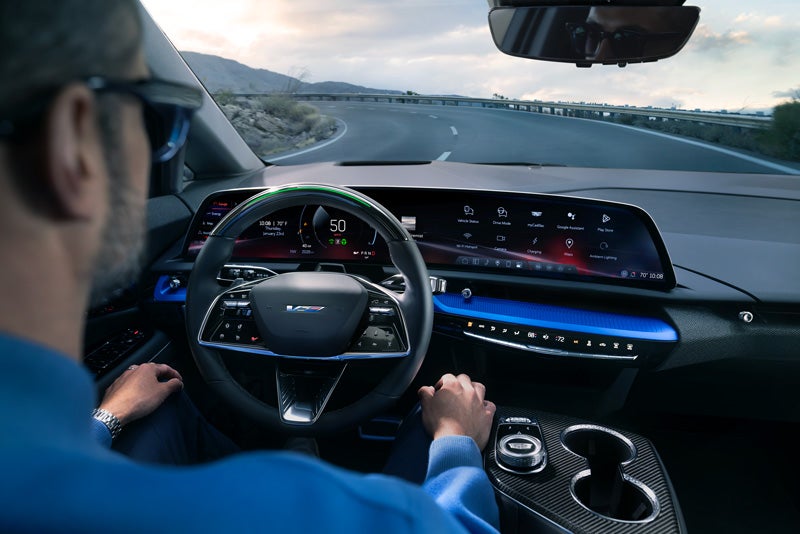 Front View of the 2026 OPTIQ-V Driving Through the Dusk Utilizing its Headlights | Bergstrom Cadillac of Neenah in Neenah WI