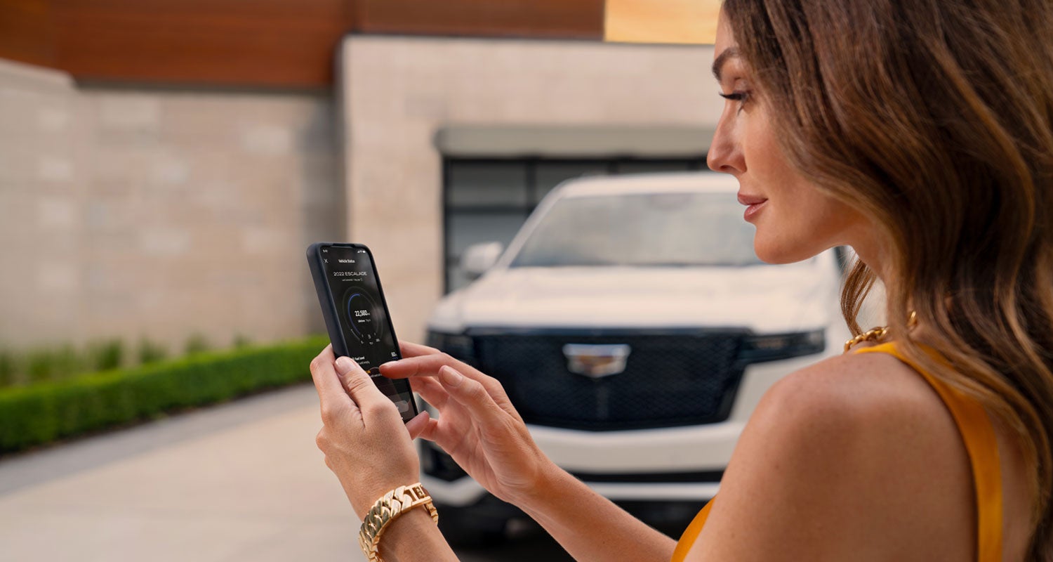 lady checking her mobile with a Cadillac vehicle background | Bergstrom Cadillac of Neenah in Neenah WI
