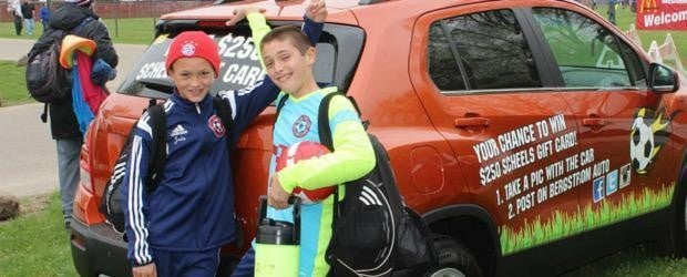 photo of two kids with a vehicle in the background